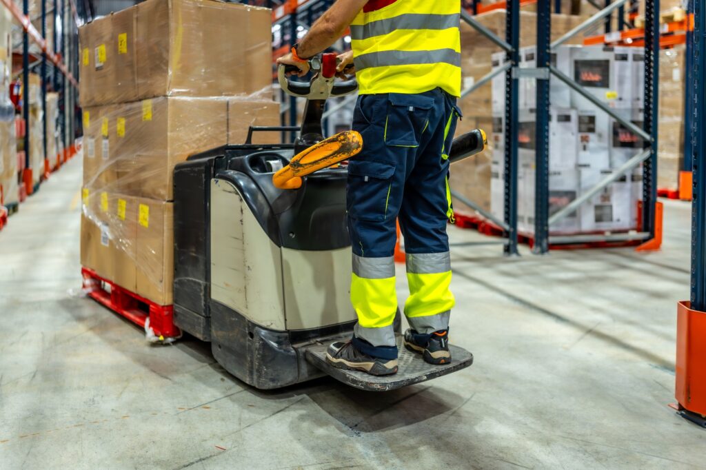 Part of worker using forklift in a warehouse
